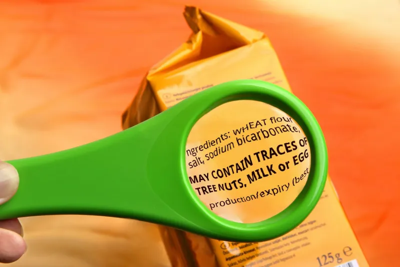 reading ingredients list on food package with magnifying glass