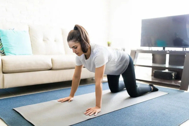 healthy young woman doing yoga on fitness mat at home