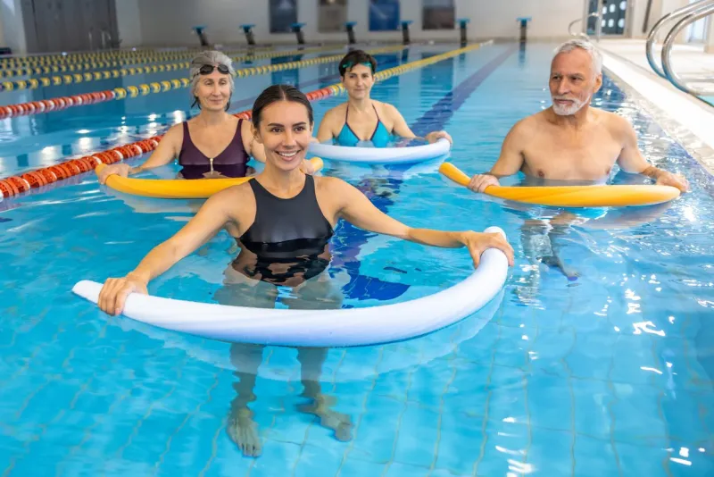 water fitness class group of people working with float noodles at water fitness class