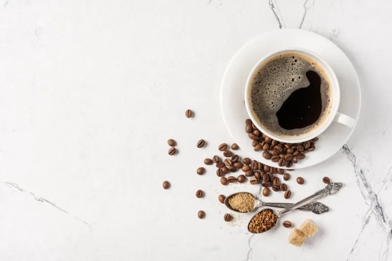 top view of black coffee in white cup with sugar for breakfast on marble background with copy space