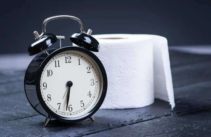 alarm clock with toilet paper on a black wooden table
