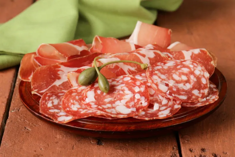 viande de saucisse séchée tranchée (jambon, prosciutto, salami) servie sur une planche de bois