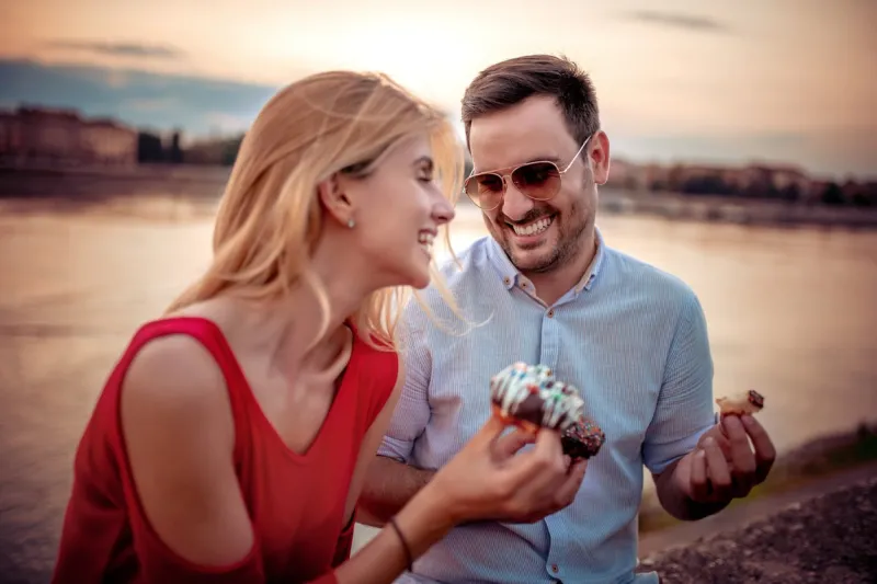 happy young couple having fun outdoors,eating donuts