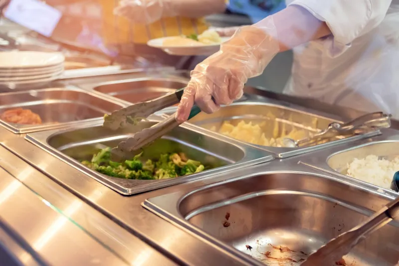 chef standing behind full lunch service station with assortment of food in trays