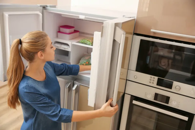 young woman choosing food in refrigerator at home