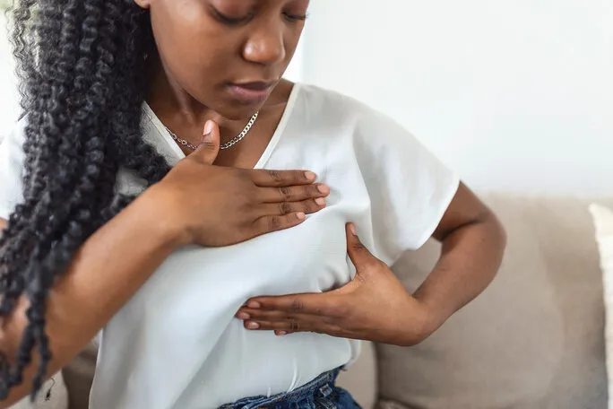 young african american woman palpating her breast by herself that she concern about breast cancer healthcare and breast cancer concept