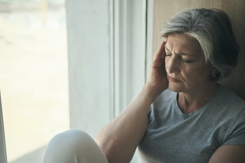 elderly senior woman massaging her temples to reduce her headache older lady feeling scared, anxious, and thinking of sickness or mental health while suffering from a severe migraine or memory loss