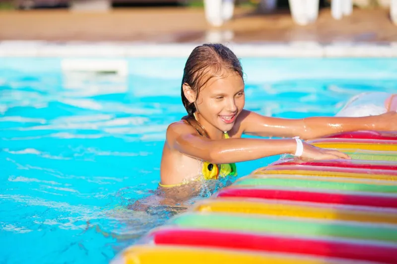 little girl playing and having fun in swimming pool with air mattress kid playing in water swimming concept girl swim in resort pool during summer vacations