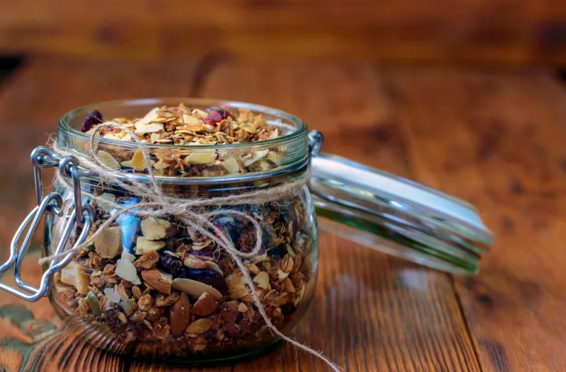 healthy breakfast homemade granola in glass jar on wooden background