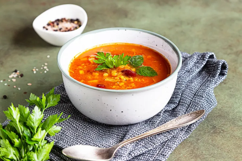 a bowl of homemade red bean and lentil soup, bread and parsley on stone background vegetable spicy soup selective focus