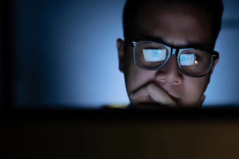 a focused and serious looking man working and thinking hard on a computer
