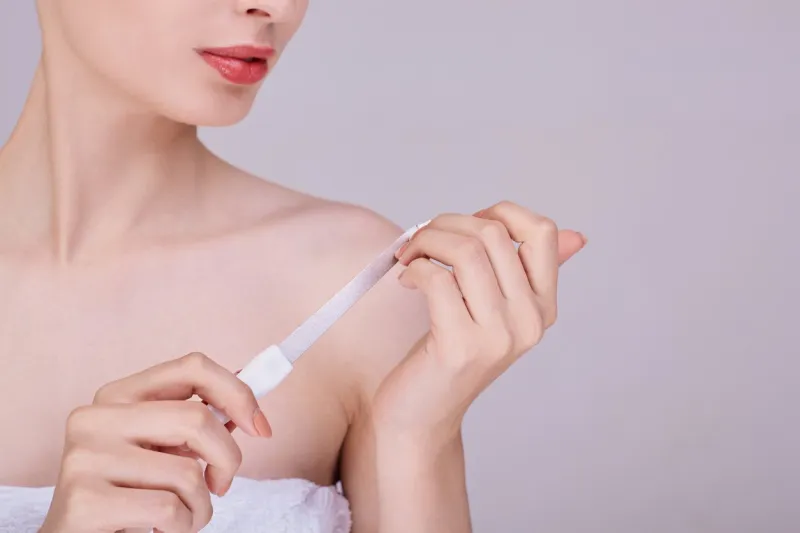a half-naked girl with beautiful healthy skin holds a nail file in her hands and files a manicure personal care