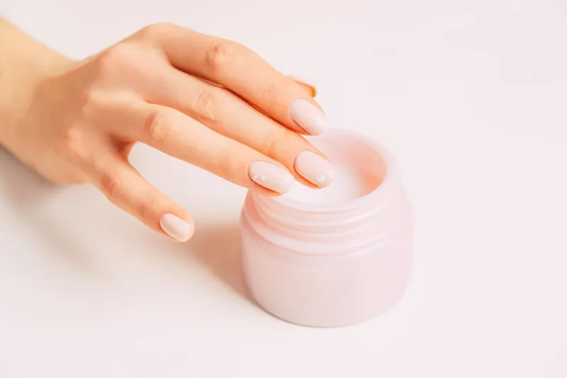 young female hand using moisturizing cream from jar, concept of beauty and skincare