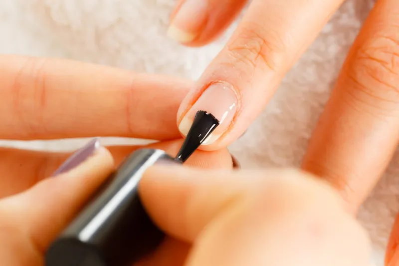 closeup of beautician painting nails of female client woman in beauty spa salon doing manicure