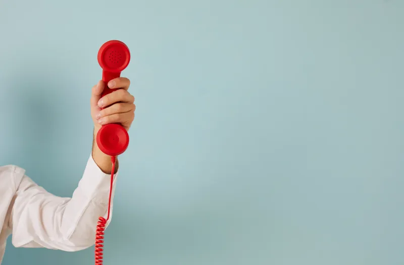 man hand isolated on green studio background hold corded telephone for call center service ad male with wired phone express communication, make call for feedback or opinion copy space