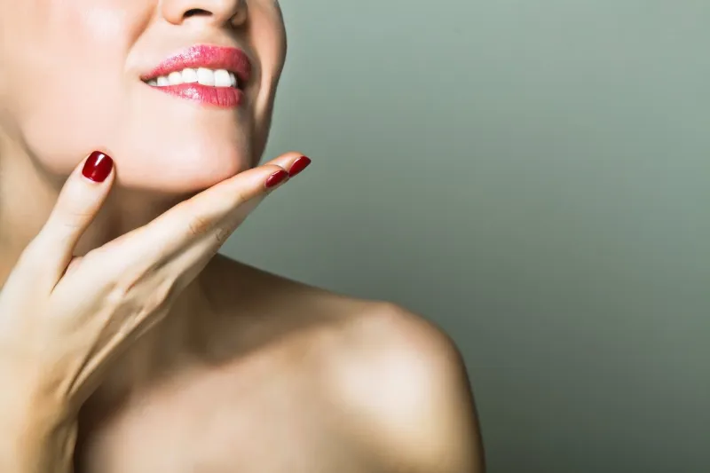 smiling nude woman touching her chin with hand