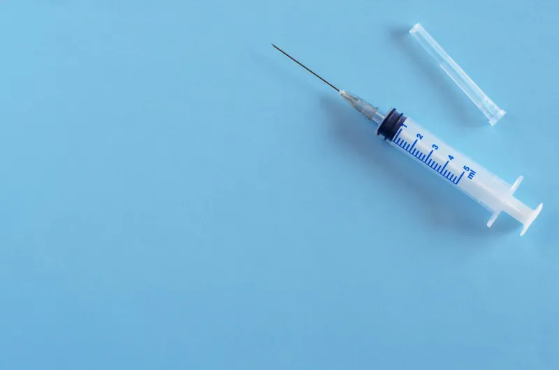 syringe with medical needle on blue background