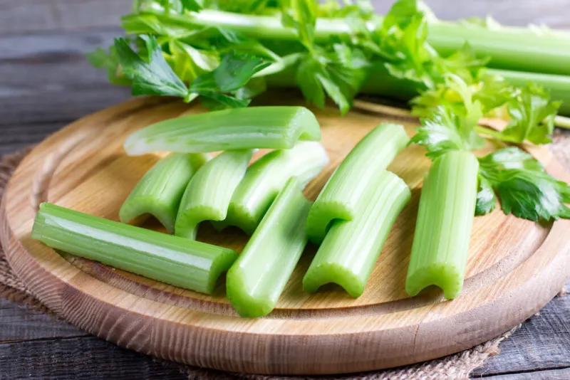 fresh celery stems on wooden cutting board