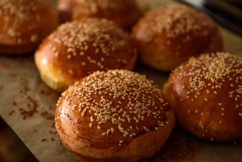 homemade burger rolls sprinkled with sesame seeds are baked in the oven