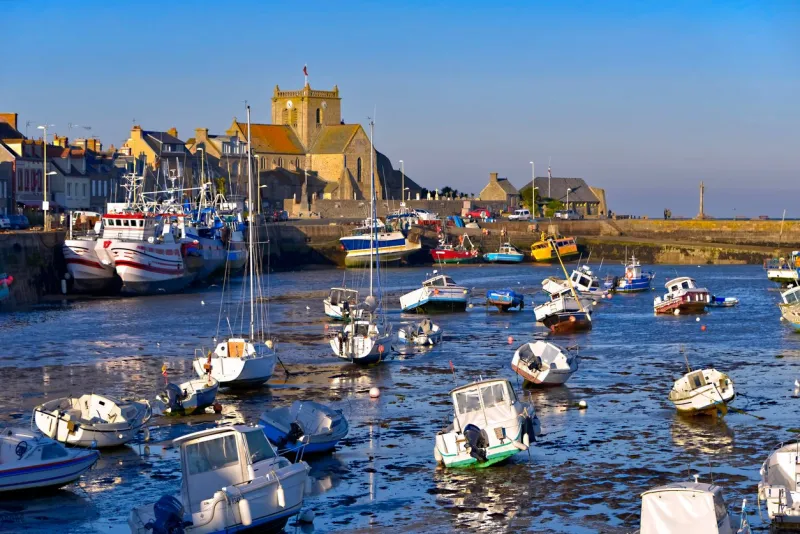 port at low tide at the end of the sunny day and church of saint-nicolas of barfleur, a commune in the peninsula of cotentin in the manche department in lower normandy in north-western france