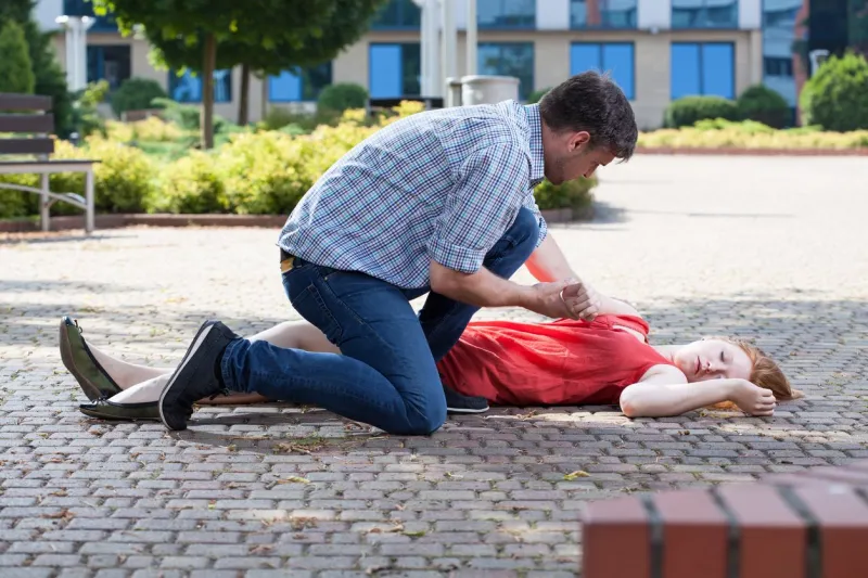 man trying to help unconscious woman on the street