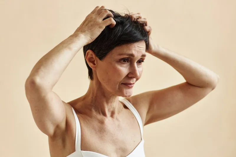 minimal portrait of mature woman scratching head and scalp suffering from skin condition, copy space
