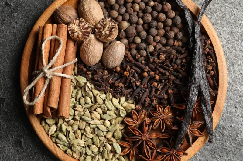 different spices and nuts on gray table, top view