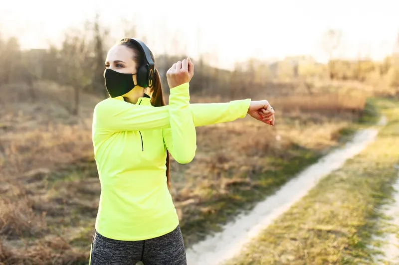 get in shape during quarantine athletic woman is doing cardio workout outdoors she in a medical mask doing stretching on the grass spending time with healthy benefit during coronavirus epidemia