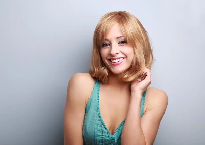 happy laughing short hair blond woman bright makeup and hair style on blue background with empty copy space