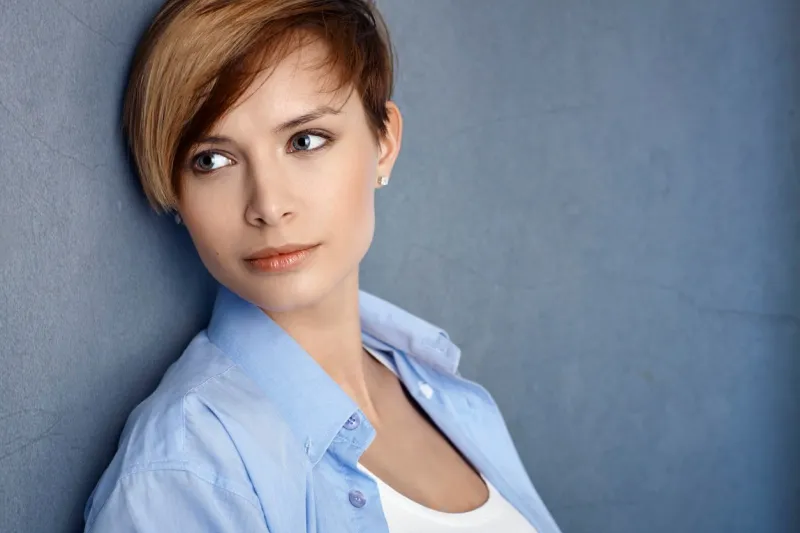 closeup portrait of attractive young woman leaning to grey wall, smiling