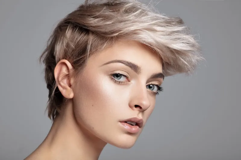 close-up face of young woman with blonde short hair isolated over gray background