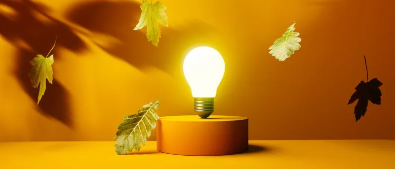light bulb on a podium with autumn leaves - 3d render