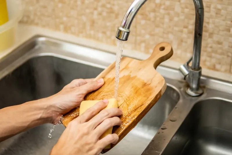 cleaning wood cutting board in kitchen sink