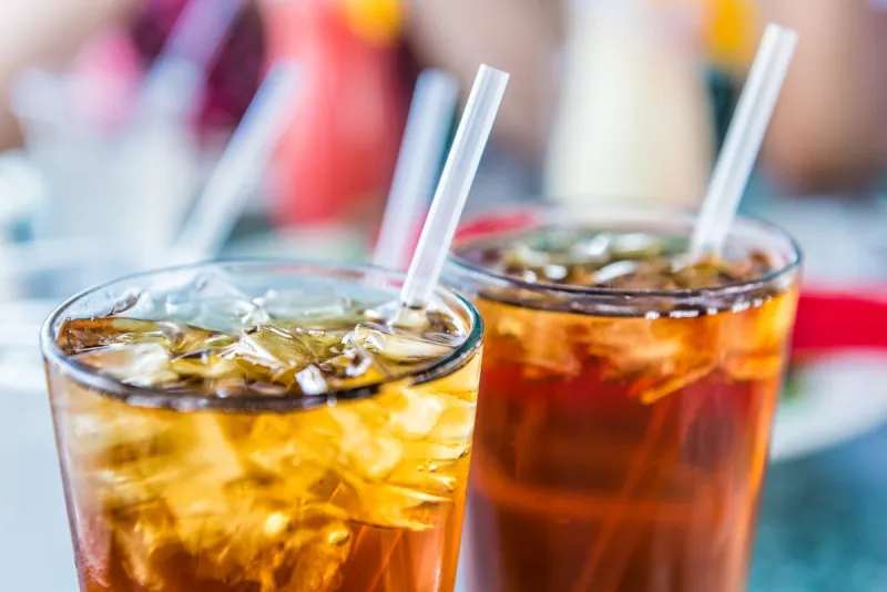 macro closeup of iced tea or soda with ice cubes and straw in glass