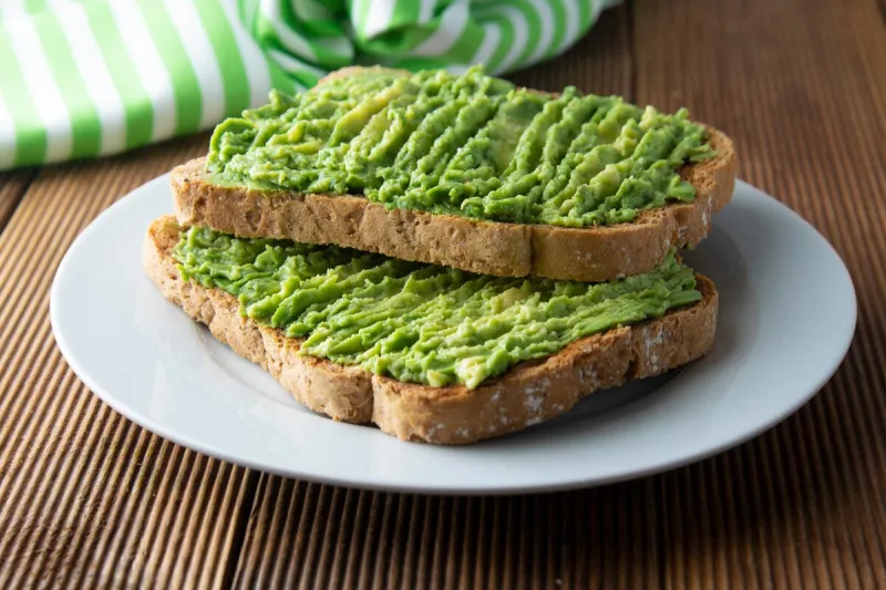 healthy avocado sandwich, toast bread mushed avocado paste, on wooden background guacamole