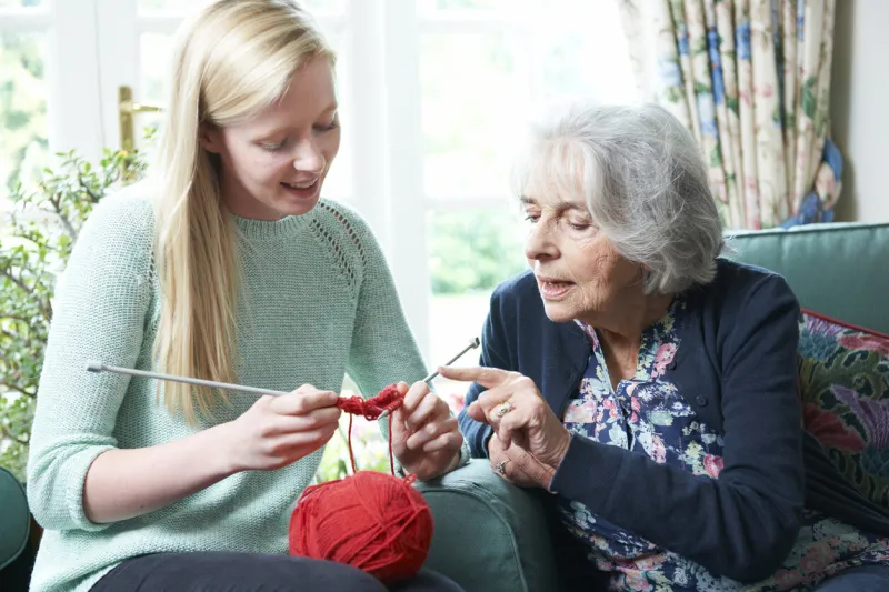 grandmother showing granddaughter how to knit