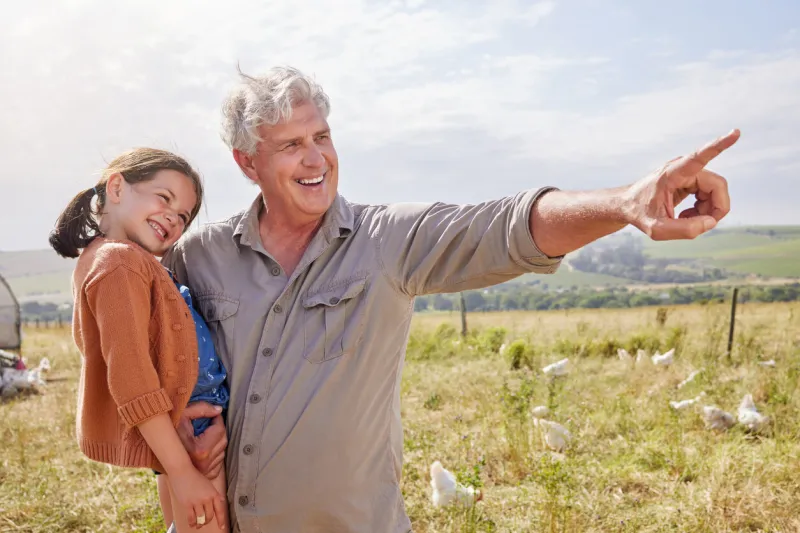 shot of a mature man bonding with his granddaughter on a poultry farm