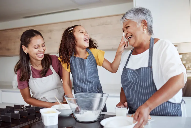 women, happy family and bake food in kitchen smile together love cooking dessert and bonding at family home excited, happiness and smiling elderly grandmother, mom and girl kid baking fun at house