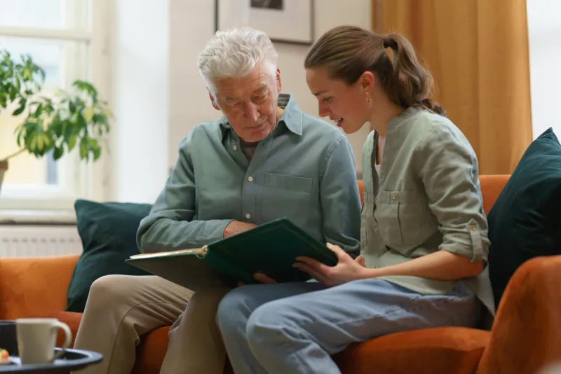 senior man with his grandaughter looking family photo album