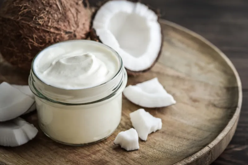 coconut cream in a glass jar with fresh coconut on a wooden background healthy vegan food concept