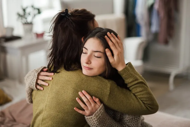 young teenage girl hugging her mother at home