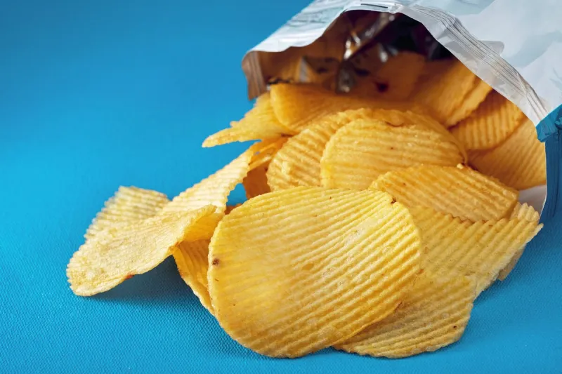 potato chips in a bag or package spill out on the table macro close up view