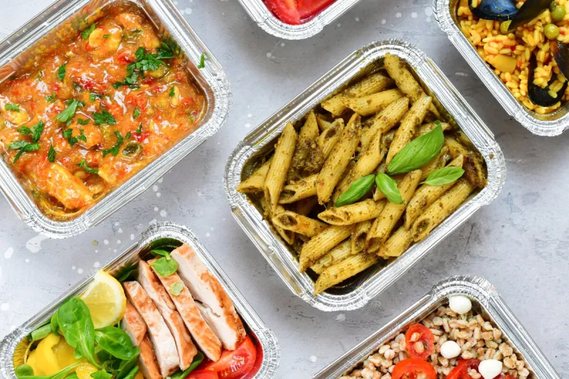 different aluminium lunch box with healthy natural food pasta pesto, spelt, paella, quinoa, chicken salad, curry