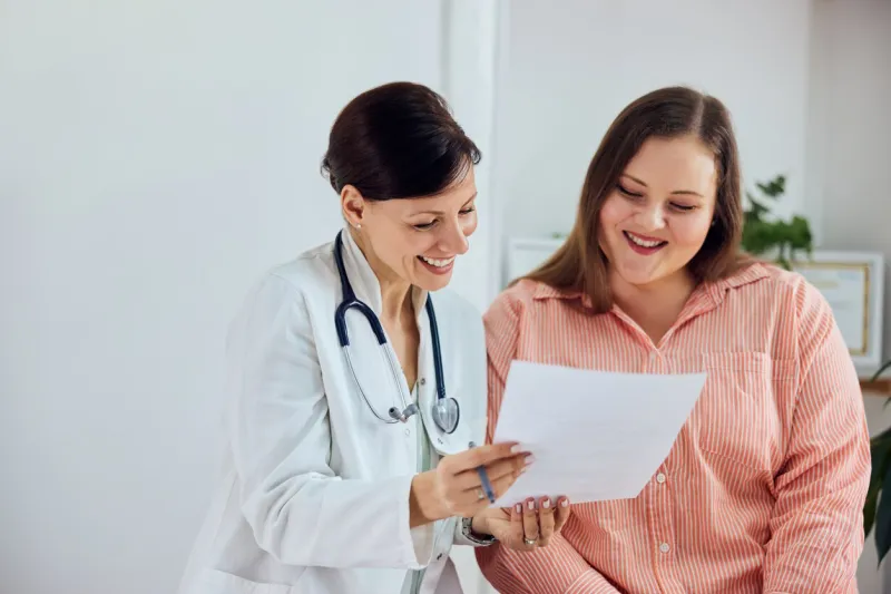a happy overweight woman is satisfied with her weight loss program results and sitting with a female nutritionist