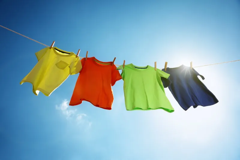 t-shirts hanging on a clothesline in front of blue sky and sun