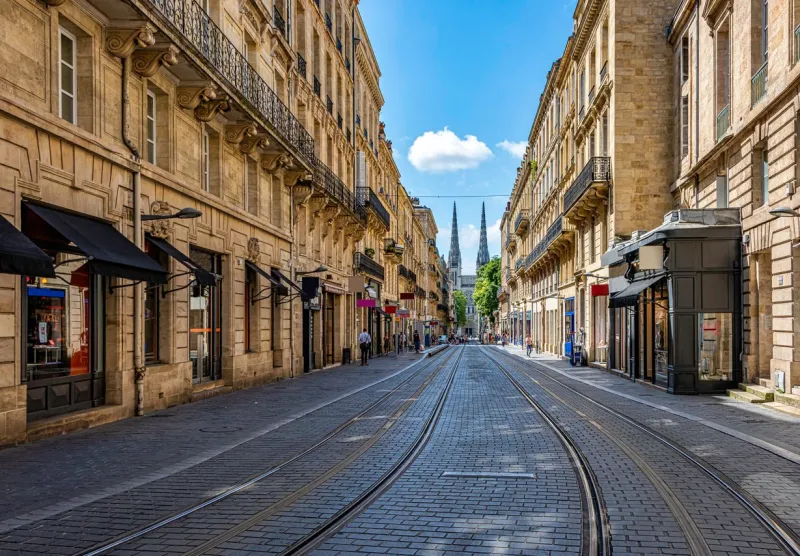 a pic of a street in bordeaux france with the cathedral at the end
