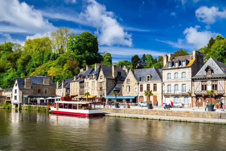 beautiful view of scenic narrow alley with historic traditional houses and cobbled street in an old town of dinan with blue sky and clouds brittany (bretagne), france