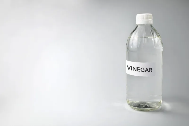 close-up of vinegar text on glass bottle against gray background
