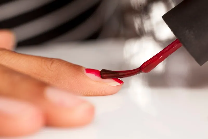 young dark skinned woman, polishing her nails