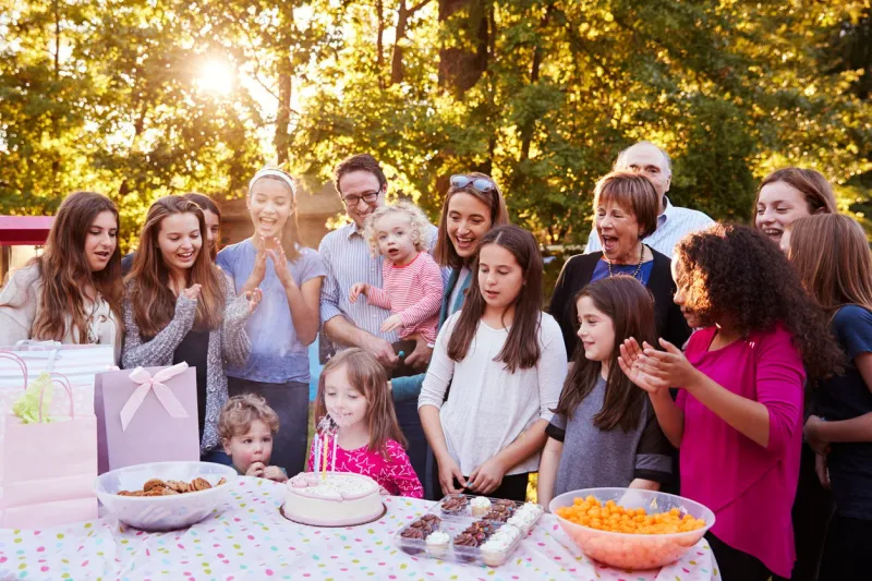young girl blowing out candles at her birthday garden party